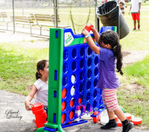 Two young girls playing Connect Four in the park.