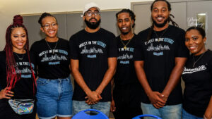 A group of smiling adults wearing t-shirts that say "Invest in the Youth - Houston"