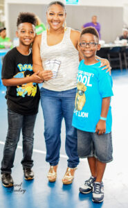 A mother smiling with her two children standing next to her.