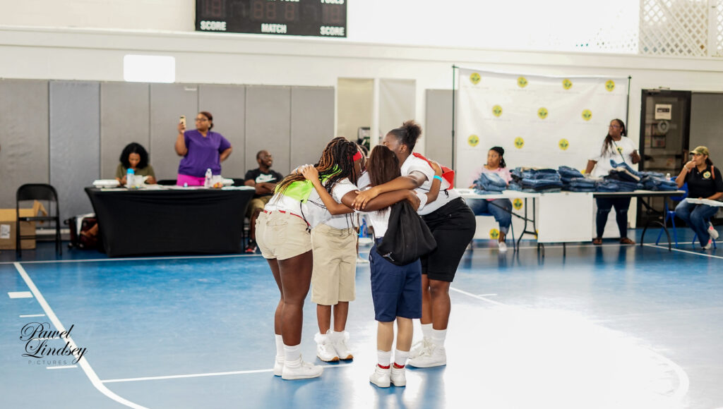 Girls huddled together in a gymnasium talking.