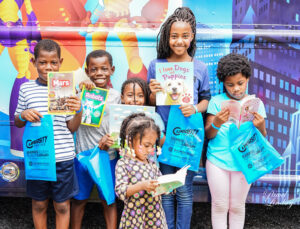 A group of children smiling for the camera holding books.