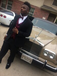 Recipient of Project Prom 2017 wearing a tuxedo and standing in front of a Rolls Royce